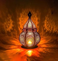 an intricately designed candle holder is lit by the light from behind on a dark background