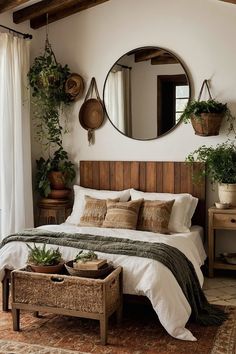 a bed sitting under a round mirror next to a table with potted plants on it