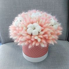 a pink and white pom - pom sitting on top of a gray chair