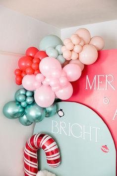 balloons are hanging on the wall next to a wreath and christmas stocking with a candy cane