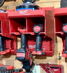 several milwaukee power tools are hanging on the wall next to each other in storage bins