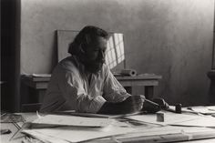 black and white photograph of a man sitting at a desk with papers on the table