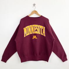 Vintage NCAA University of Minnesota 'Golden Gophers' Crewneck Sweatshirt Embroidery Logo Red Color Men's XL - Made in Pakistan - Materials : Cotton, Polyester  - Tag Reads : XL Kindly see the actual measurements (All measurements were taken lying flat) - Actual size manual measurements * Width (Armpit to armpit) : 26 inches * Length (Shoulder to end of garment) : 27 inches * Sleeve length : 25.5 inches - Condition : * Good condition 8/10 (80%) * Minor stain refer picture * Free from tear and major defect - Shipping : * DHL Express/FedEx Express = 3-6 business day arrived * Please PROVIDE your PHONE/CONTACT NUMBER for SHIPPING/DELIVERY purpose DON'T FORGET TO VISIT MY SHOP FOR MORE GREAT STUFF, THANK YOU. College Red Tops With Embroidered Text, Red College Top With Embroidered Text, Red College Tops With Embroidered Text, Red Embroidered Text College Tops, Red College Sweatshirt With Embroidered Logo, Collegiate Embroidered Winter Tops, Collegiate Tops With Embroidered Graphics For Winter, Winter Fan Apparel Tops With Embroidered Logo, Long Sleeve Embroidered Graphics Sweatshirt For Fans