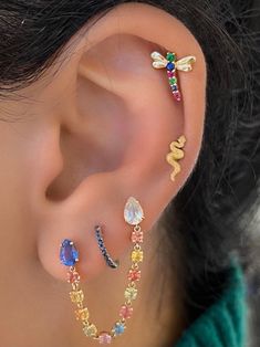 a woman wearing three different colored ear piercings on her left ear and one with a dragon