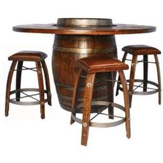 a wooden table with two stools next to a barrel and a wine glass on top