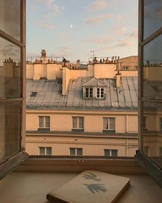 an open book sitting on top of a window sill in front of a building