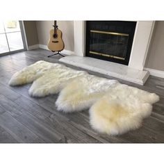 two white sheepskin rugs on the floor in front of a fireplace