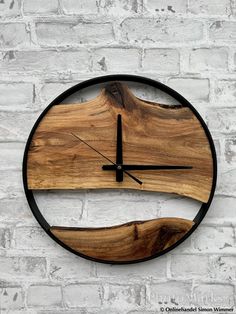 a clock made out of wood and metal on a white brick wall with black hands