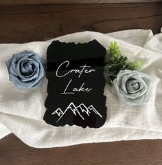 there is a sign that says crater lake and two roses on the table next to it