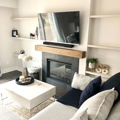 a living room filled with furniture and a flat screen tv mounted on a wall above a fire place