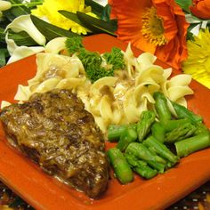 an orange plate topped with pasta and veggies