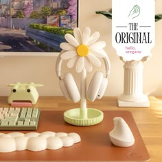 there is a computer keyboard and headphones on the desk next to a daisy flower