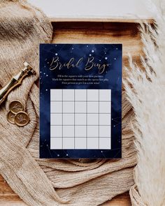 a blue and gold bridal bingo game on top of a table next to a pair of scissors