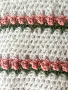 crocheted blanket with pink and green trim