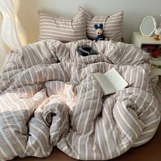 an unmade bed with a book on it and stuffed animals in the corner next to it