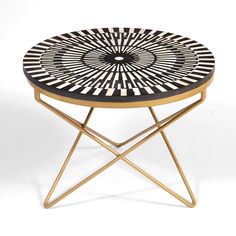 a black and white circular table with gold legs on a white background in the shape of a starburst