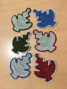 four crocheted leaves sitting on top of a wooden table next to each other