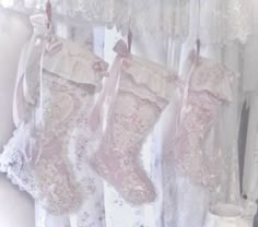 three lace stockings hanging from a curtain with pink bows and ribbons attached to them, in front of white curtains