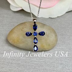 "The pendant pictured is a lab created blue sapphire cross #6073 Also shown with lab created ruby #6867 -Approximate total carat weight: approx. 1.40ctw diamond equivalent -Center Stone Size: 3mm - approx. 0.10ct diamond equivalent -Center Stone Shape: round -Accent Stone Size: 5x3mm approx. 0.26ct each diamond equivalent -Accent Stone Shape: 5 pear shape stones -Gem Type: lab created sapphire -Stone Clarity: VS2 -Stone Color: Blue -Moh's Scale: 9 hardness -Metal Type and Purity: 14k white gold Blue Cross Pendant Necklace For Anniversary, Blue Cross Jewelry For Anniversary, Blue Gemstone Cross-shaped Jewelry, Blue Sterling Silver Cross Necklace Gift, Blue Sapphire Necklace, Round Necklace, Sapphire Necklace, Sapphire Stone, Pear Shape