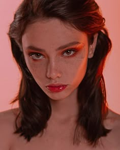 a woman with freckled hair and makeup looks at the camera while wearing red lipstick