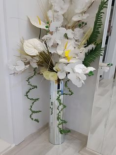 a vase filled with white flowers and greenery