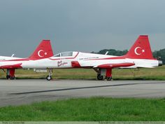 two red and white jets sitting on top of an airport runway