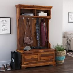 a wooden bench sitting in front of a wall filled with purses and clothes hanging on hooks