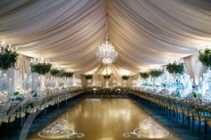 an elegant banquet hall with chandeliers and tables covered in white draping