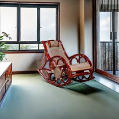 a rocking chair sitting on top of a green floor next to a window