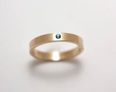 A sparkling 1.75 mm diamond cut A grade emerald flush set in a 14k gold 3 mm band in this striking minimalist ring. A flush setting gives an added amount of security to the stone. The ring can be worn by itself or as an accompaniment to another ring. If you would like an emerald of a different grade or a ring size larger than those listed, please request an estimate.  This ring would make a beautiful engagement or wedding ring. Or a "just because" ring!This is a natural emerald with no enhanceme Modern Birthstone Ring With Single Diamond In Round Band, Modern Birthstone Ring With Single Diamond, Minimalist Formal Emerald Birthstone Ring, Modern Stackable Emerald Ring For Anniversary, Minimalist Emerald Ring With Single Diamond For Promise, Minimalist Stackable Emerald Ring For Formal Occasions, Modern Emerald Promise Ring With Round Band, Modern Yellow Gold Emerald Ring With Tension Setting, Modern Diamond Ring For May Birthstone