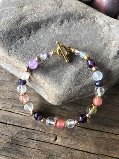 "We are excited to present to you our one-of-a-kind multi colored Fluorite bracelet with Gold accents. This stunning 8 inch* bracelet is sure to make a statement with its iridescent quality and almost otherworldly glow that plays in the light. The versatile design allows you to dress it up for a night out for dinner by the shore or dress it down for a casual weekend look at Sunday brunch. This Fluorite bracelet is not only beautiful, but also versatile and perfect for any occasion.  You can coordinate it with other accessories in your wardrobe, or complete your ensemble with a coordinating necklace and earrings, which are available separately. So don't wait, add this exquisite piece of jewelry to your collection today and be ready to turn heads wherever you go! Fluorite is the \"genius sto Spiritual Multicolor Bracelets As Gifts, Multicolor Natural Stones Spiritual Charm Bracelet, Handmade Multicolor Crystal Spiritual Bracelet, Spiritual Charm Bracelet With Natural Stones For Gift, Spiritual Pink Jewelry For Birthday, Spiritual Beaded Bracelets With Birthstones, Handmade Spiritual Multicolor Crystal Bracelet, Handmade Multicolor Spiritual Crystal Bracelet, Spiritual Multicolor Handmade Crystal Bracelet