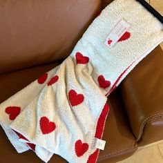 a blanket with hearts on it is sitting on a leather couch next to a brown chair