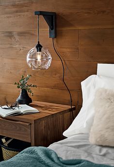 a bed with a wooden headboard and lamp on it next to a night stand