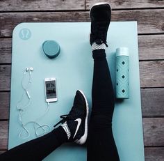 a person laying on top of a blue mat next to an ipod and headphones