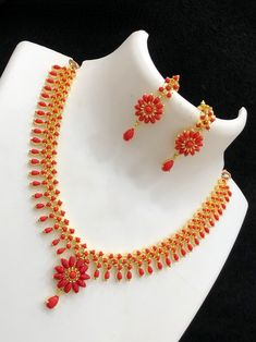 This Beautiful Gold Plated Elegant simple AD Red coral and pearl choker necklace Earring set offers an exquisite, delicate design. An alluring combination of tiny Marquis cut CZ color Ad stones and white pear shaped small pearls creates a stunning look. The set includes a matching pair of earrings, perfect for adding an extra touch of elegance. Coral Jewelry Set Kameswari Jewellers, Simple Coral Necklace Indian Gold, Red Stone Necklace Gold Indian, Ruby Choker, Red Stone Necklace, Coral Jewelry Set, Red Coral Necklace, Diamond Choker Necklace, South Indian Jewelry