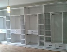 an empty room with white shelves and drawers