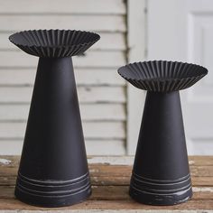 two black vases sitting on top of a wooden table