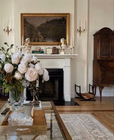 a living room filled with furniture and flowers on top of a table in front of a fireplace