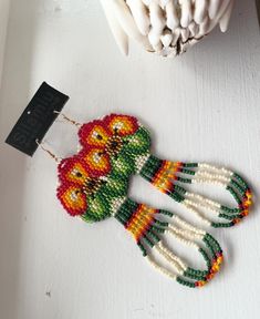 a pair of beaded earrings sitting on top of a table next to a vase