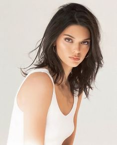 a beautiful young woman in white shirt posing for a photo with her hands on her hips