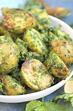 a white bowl filled with broccoli covered in pesto next to lemon wedges