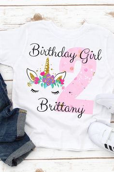 a birthday shirt with the number two in pink and unicorn ears on it, next to jeans