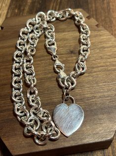 This is a beautiful, vintage, genuine sterling silver charm necklace that has a gorgeous, dangling, polished sterling silver heart charm that is engraveable. The necklace is 16 inches. The necklace features stunning open links that are each 3/8" in length. The dangling heart charm is on the end of the necklace, by its stunning clasp and measures about 1 1/4" in length by 3/4" in width at the widest point. Very pretty. The necklace is about 3/8" in width at the widest point. It weighs about 29.9 Silver Heart Necklace With Hallmark For Birthday, Classic White Gold Charm Bracelet With Heart Charm, Classic Heart Charm Bracelet For Valentine's Day, Classic Silver Heart Necklace, Classic White Gold Charm Bracelet With Heart, Classic Sterling Silver Heart Necklace, Classic Silver Necklace With Heart Charm, Classic Heart Pendant Jewelry With Sterling Silver Clasp, Classic White Gold Charm Necklaces