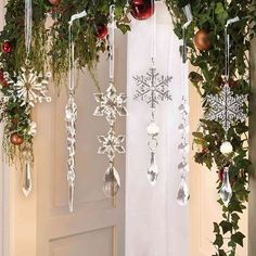 christmas decorations hanging from the side of a door with greenery and snowflakes