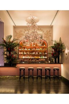 the bar is decorated with candles and plants in front of an ornate chandelier