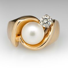 This curved lines ring is accented with one (1) post set, cultured saltwater pearl and with one (1) round brilliant cut diamond that is set in a four prong head. The ring has a European shank and measures 13.8mm at the top, rises 9.3mm above the finger, tapering to 3.8mm wide and 1.8mm thick at the base of the shank. It is crafted in 14k yellow gold and is currently a size 6.5. Elegant Diamond White Bypass Ring With Tension Setting, Elegant 14k Gold Bypass Ring With Single Diamond, Classic Pearl Ring With Single Diamond, Elegant Bypass Ring With Single Round Cut Diamond, Elegant Bypass Ring With Tension Setting For Formal Occasions, Elegant Bypass Ring With Round Cut Diamond, Classic Pearl Ring With Single Diamond For Anniversary, Classic Pearl Ring With Single Diamond For Formal Occasions, Classic Formal Pearl Ring With Single Diamond