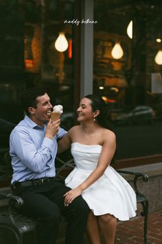 a man and woman sitting on a bench eating ice cream