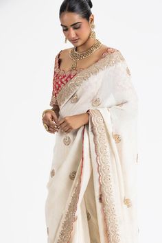 Ivory georgette lurex weave saree with scattered floral butti embroidery. Paired with a padded blouse, embroidered with gota, zari, dabka, beads and resham work.
Components: 2
Pattern: Embroidery
Type Of Work: Floral, Gota, Zari, Dabka, Beads
Neckline: Scoop Neck
Sleeve Type: Half Sleeves
Fabric: Georgette, Brocade
Color: Ivory
Other Details: 
Blouse:
Padded
Scallop trimmed edges
Back tie-up detailing with stones ornamentation
Occasion: Destination Wedding - Aza Fashions Red Brocade Blouse, Butti Embroidery, Ivory Drapes, Resham Work, Brocade Blouse, Padded Blouse, Brocade Blouses, Beaded Neckline, Pattern Embroidery