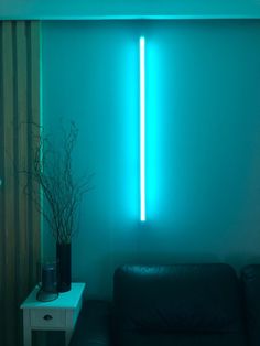 a living room with a black couch and blue light coming from the wall behind it