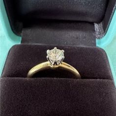 an engagement ring in a velvet box with the lid open to show it's diamond center